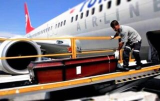 Ein Flughafenmitarbeiter trägt den Sarg zum Flugzeug