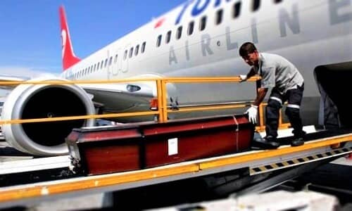 Ein Flughafenmitarbeiter trägt den Sarg zum Flugzeug