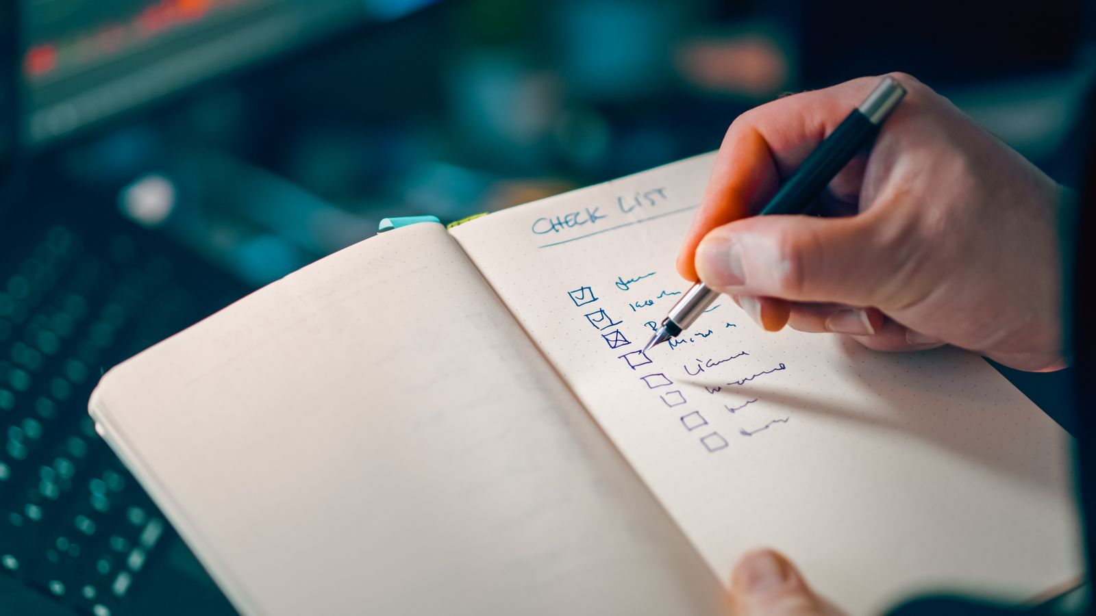 Hand schreibt eine Checkliste in ein Notizbuch